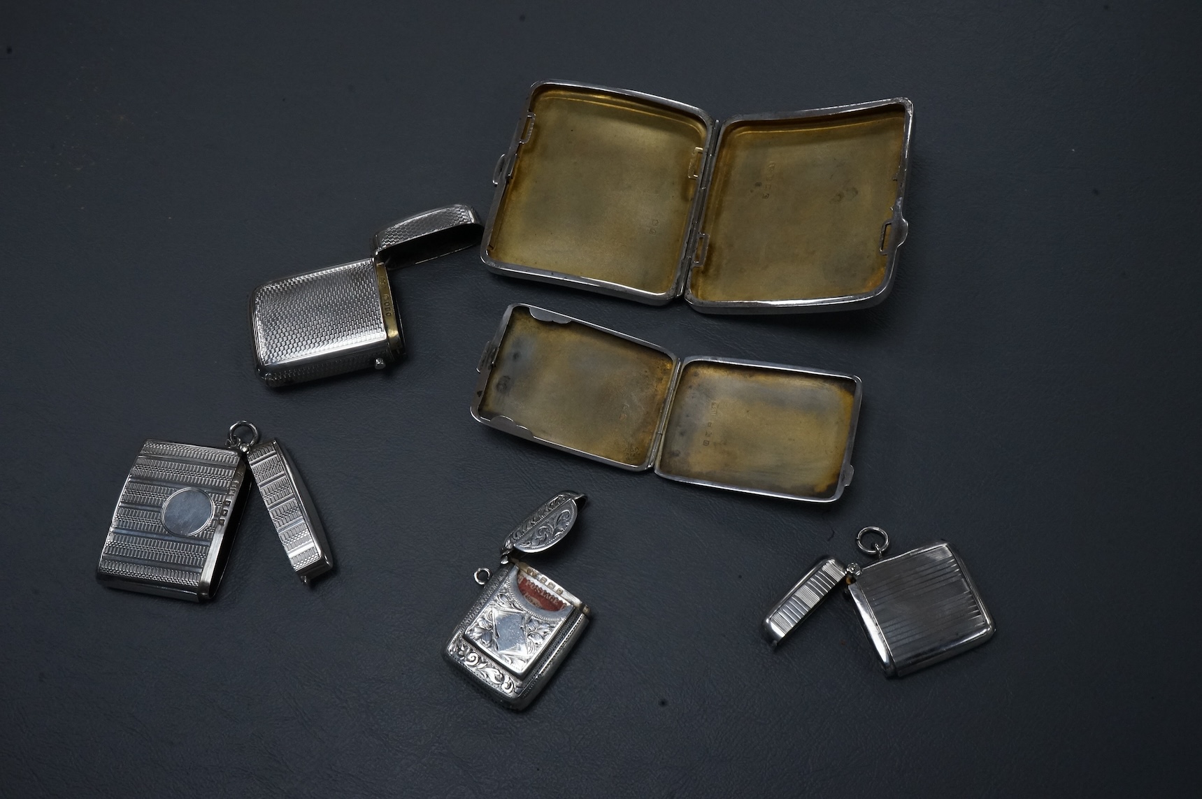 Four assorted early 20th century silver vesta cases including one with a stamp compartment, containing a penny red, maker William Light, Birmingham, 1906, 42mm, together with a silver cigarette case and a silver match sl